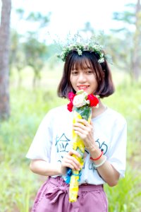 Woman Wearing White Shirt And Purple Bottoms Holding Bouquet Of Flowers
