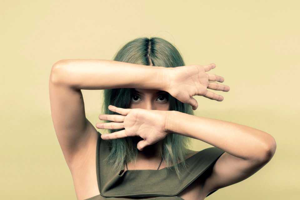 Woman Wearing Green Sleeveless Top Covering Her Face But Eyes With Both Hands