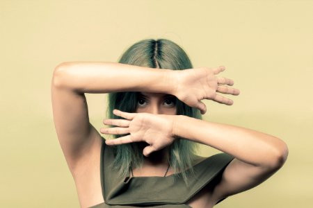 Woman Wearing Green Sleeveless Top Covering Her Face But Eyes With Both Hands photo