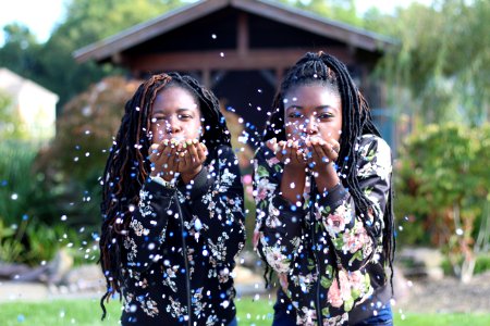 Two Girls Blowing Petals Of Flowers Off Their Hands photo