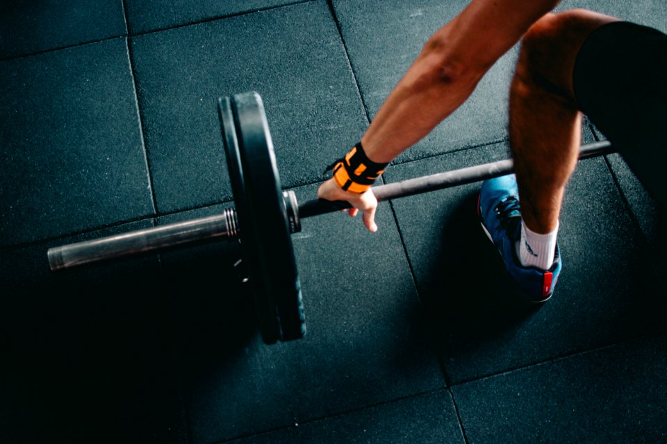 Person Wearing Black Shorts And Blue Lace-up Low-top Sneaker Holding Black Barbell