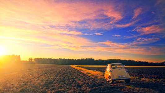 Yellow Classic Car Parked On Field Under Cloudy Sky At Golden Hour photo