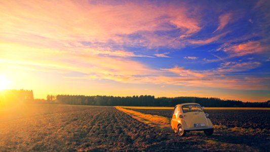 Yellow Classic Car Parked On Field Under Cloudy Sky At Golden Hour
