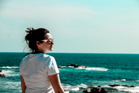 Woman Wearing White T-shirt With Distance At Sea With Rock Formations