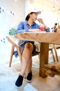 Woman Sits On Brown Wooden Chair Near Brown Table Inside Room photo