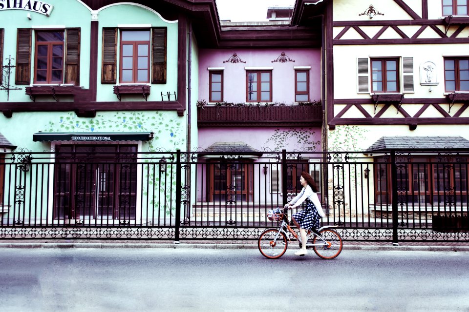 Woman Riding On Bicycle Near Concrete Houses
