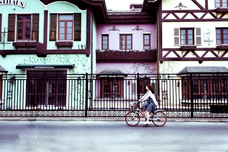 Woman Riding On Bicycle Near Concrete Houses photo