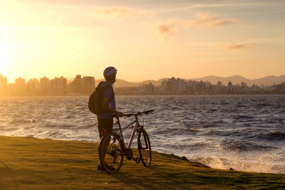 Man With Bicycle Standing On Cliff Front Of Water Waves Golden Hour Photography