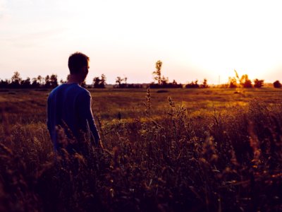 Man In Blue Sweatshirt In The Middle Of Field During Sunset