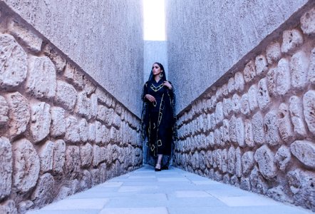 Woman In Black And Gold Traditional Dress Between Gray Concrete Walls photo