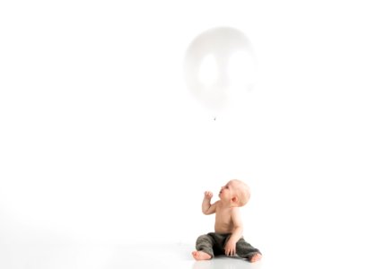 Topless Toddler With Pants Sitting On White Surface While Looking Up