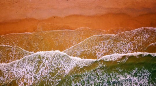 Aerial Photography Of Flow Of Water Near Sand photo