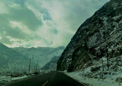 Snow Covered Mountain Ranges Near The Asphalt Road Under The Cloudy Sky photo