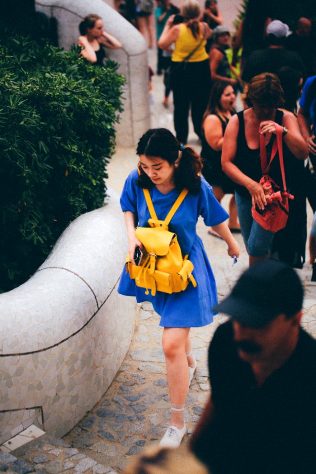 Woman In Blue Dress With Yellow Knapsack Walking Near People
