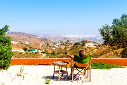 Man Sitting On Green Chair Near Trees And Mountain Under Blue Sky At Daytime photo