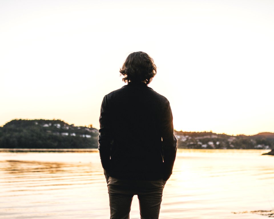 Man Standing Facing Body Of Water