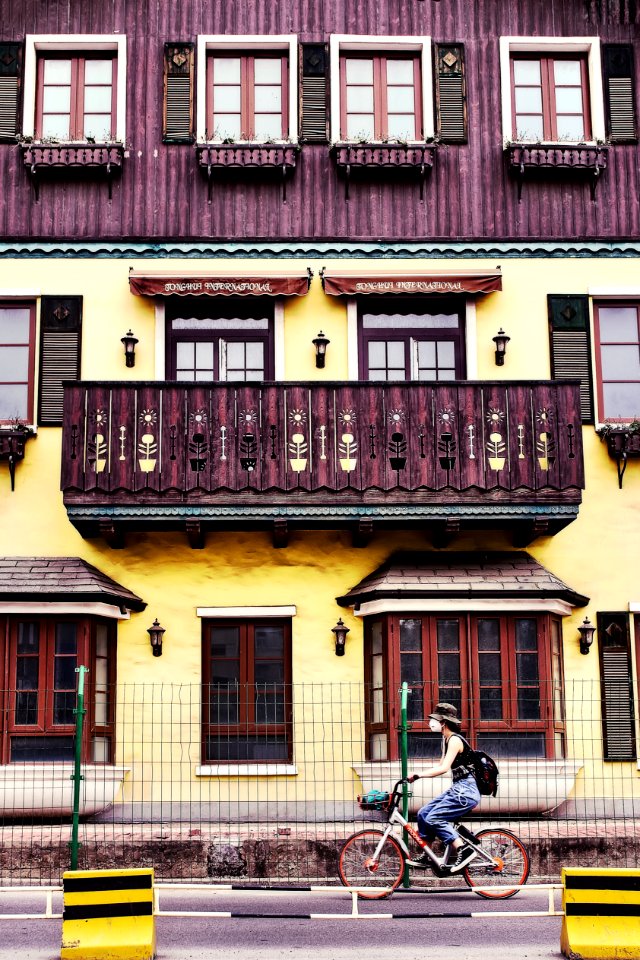 Woman Riding On Bicycle Near House