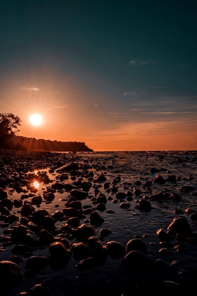 Photo Of Rock Rubles Beside Calm Body Of Water During Golden Hour