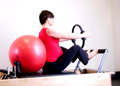 Woman In Red Top Leaning On Red Stability Ball photo