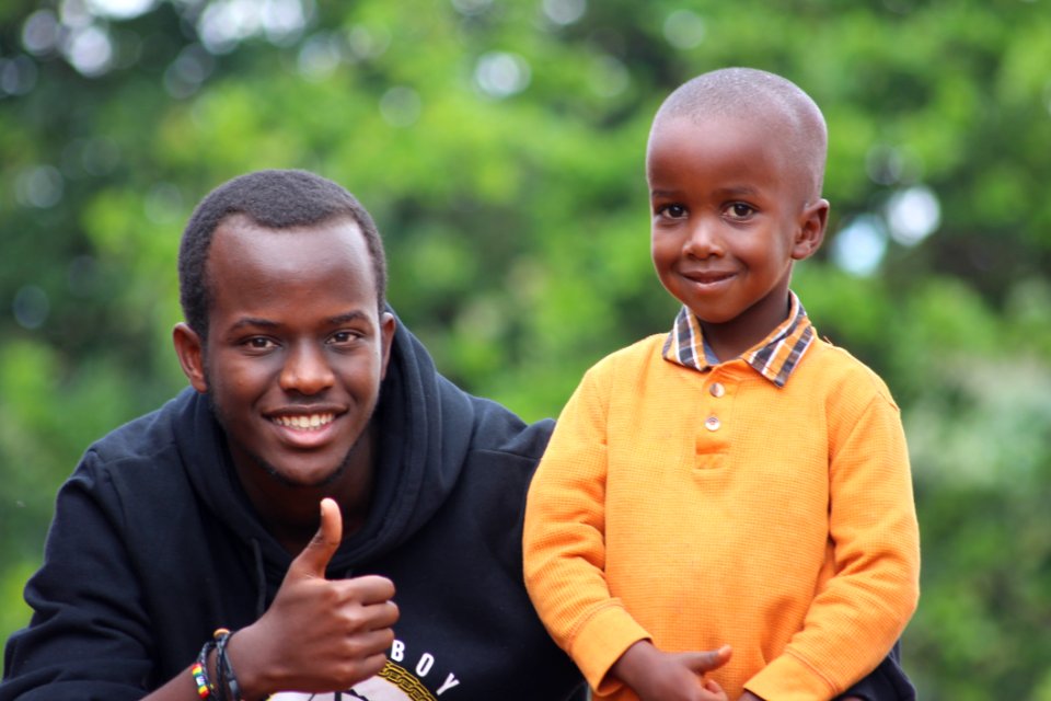 Man Wearing Black Hoodie Beside Boy Wearing Orange Long-sleeved Polo Shirt photo