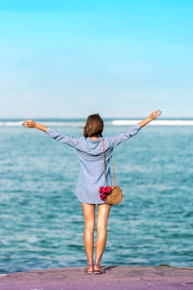 Woman In Blue Dress Shirt Standing Near Body Of Water photo