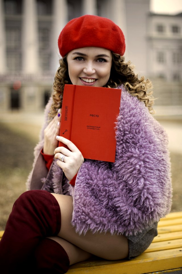 Woman Wearing Purple Coat And Gray Shorts Sitting On Brown Chair