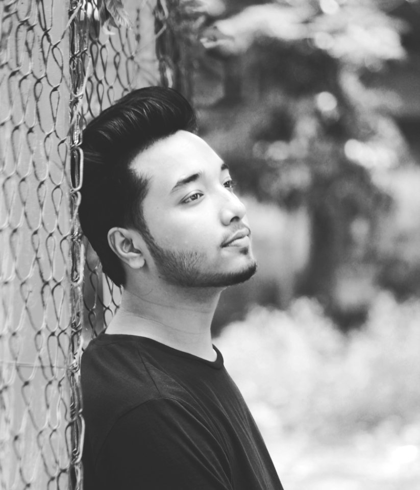 Grayscale Photo Of Man Leaning On Wire Fence photo