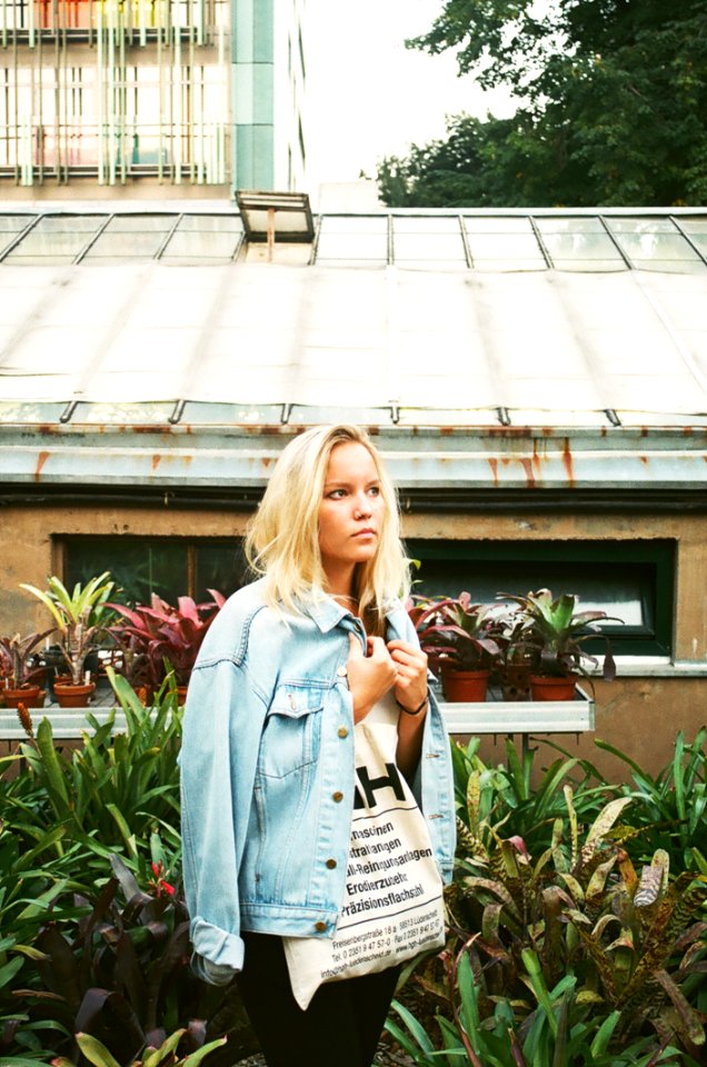 Woman Wearing White Shirt And Denim Jacket Standing Near House