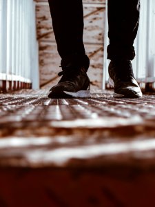 Person In Black-and-white Shoes Standing On Brown Metal Floor