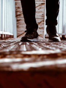 Person In Black-and-white Shoes Standing On Brown Metal Floor photo