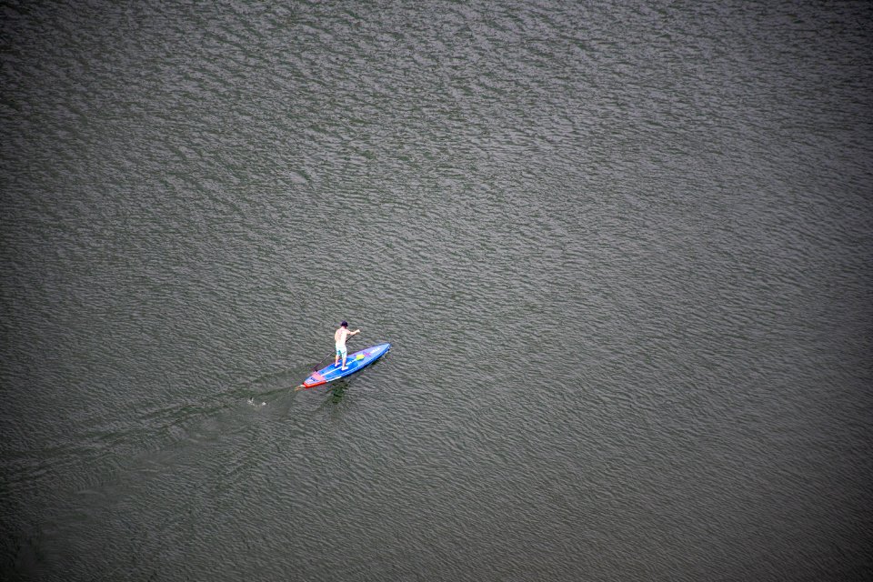 Person Riding Blue And Red Paddleboard On Water