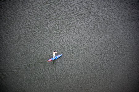 Person Riding Blue And Red Paddleboard On Water