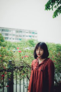 Lowlight Photography Of Woman In Red Shirt Standing Beside Plant photo