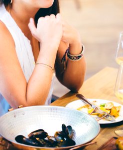 Woman Wearing White Deep V-neck Sleeveless Top Sitting On Chair Near Table photo