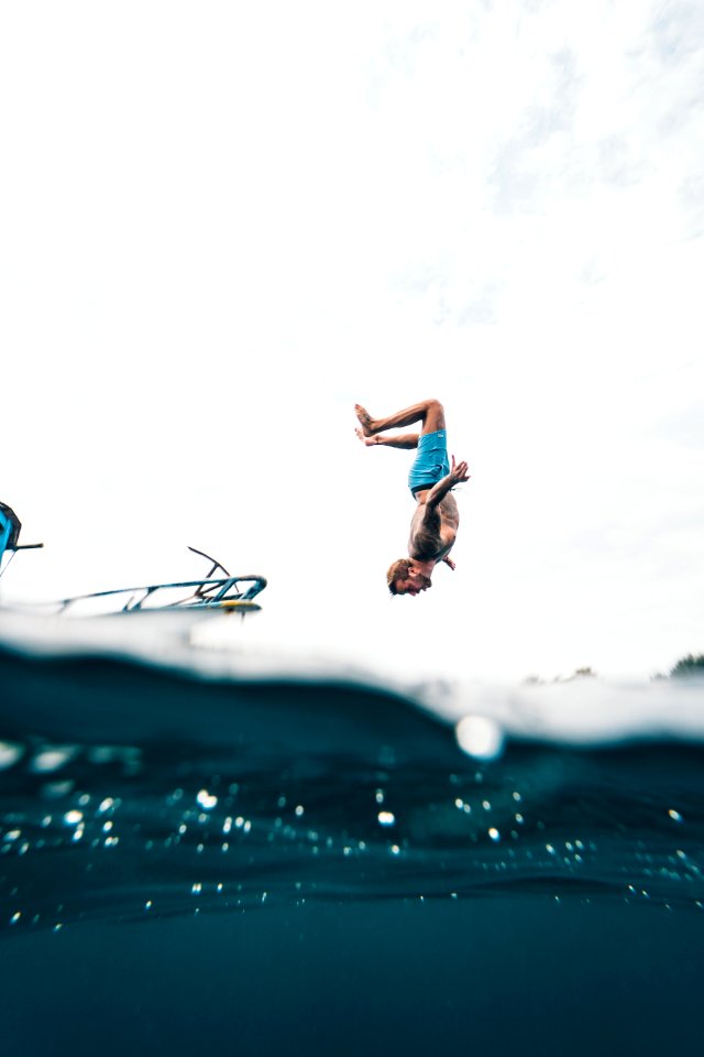 Man Wearing Blue Shorts About To Dive On Body Of Water