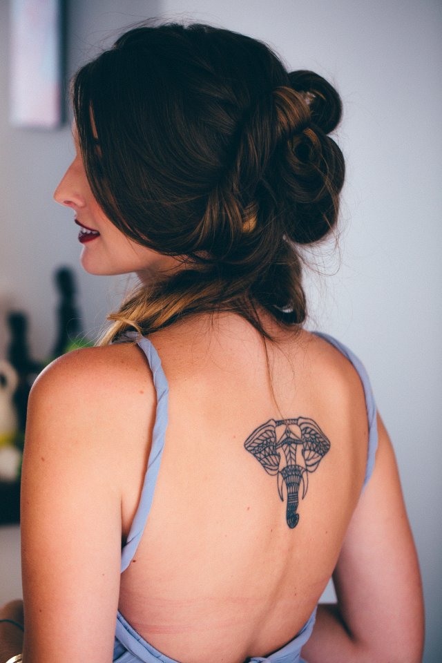 Woman With Black Elephant Tattoo In Back