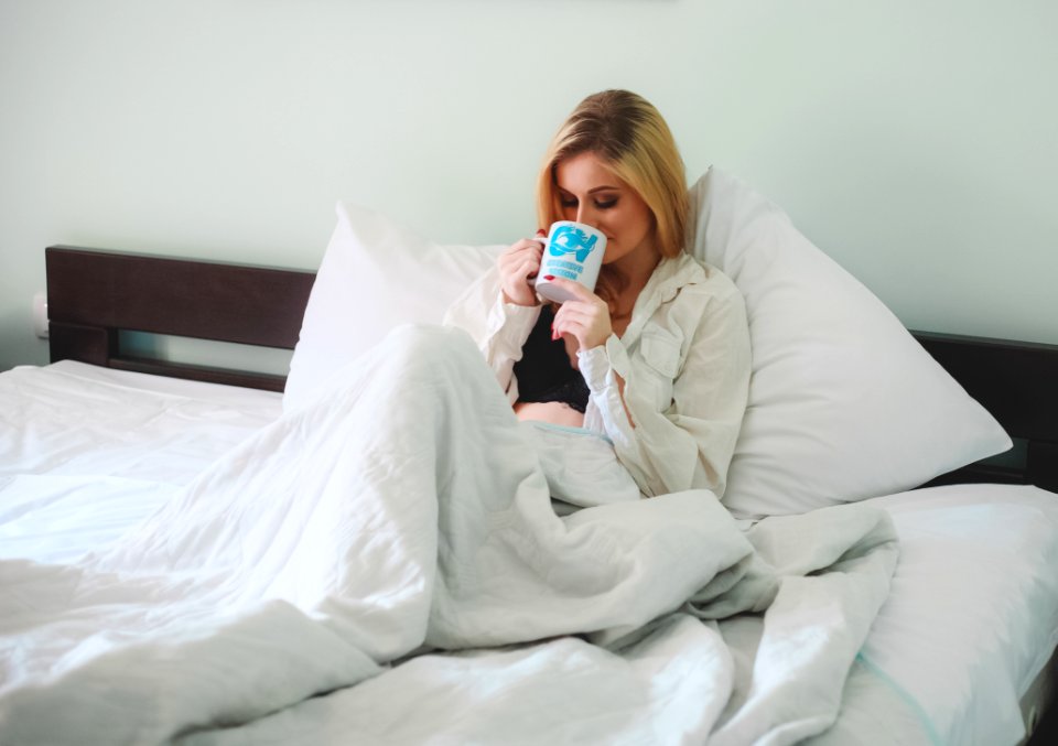 Woman Sitting On Bed Holding Mug