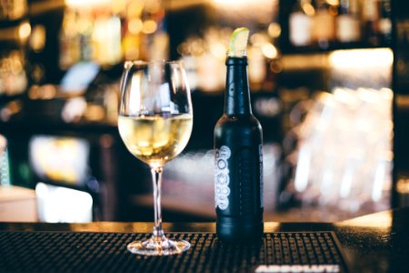 Black Bottle Beside Long-stem Wine Glass On Table photo