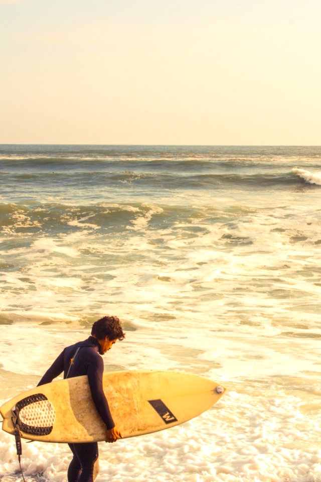 Man Carrying Surfboard Near Shoreline