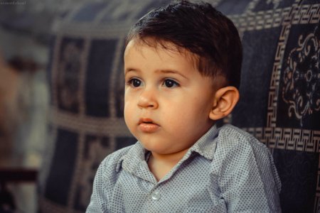 Boy In Gray Button-up Shirt Sitting On Black Sofa photo