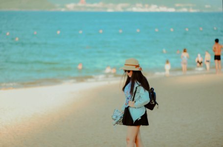 Girl In Cyan Jacket Walking On Beach photo