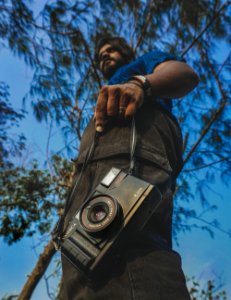 Worms View Of Man Holding Camera Under Blue Calm Sky