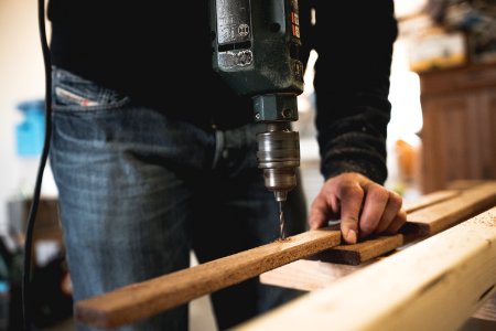 Man Holding Wooden Stick While Drilling Hole photo