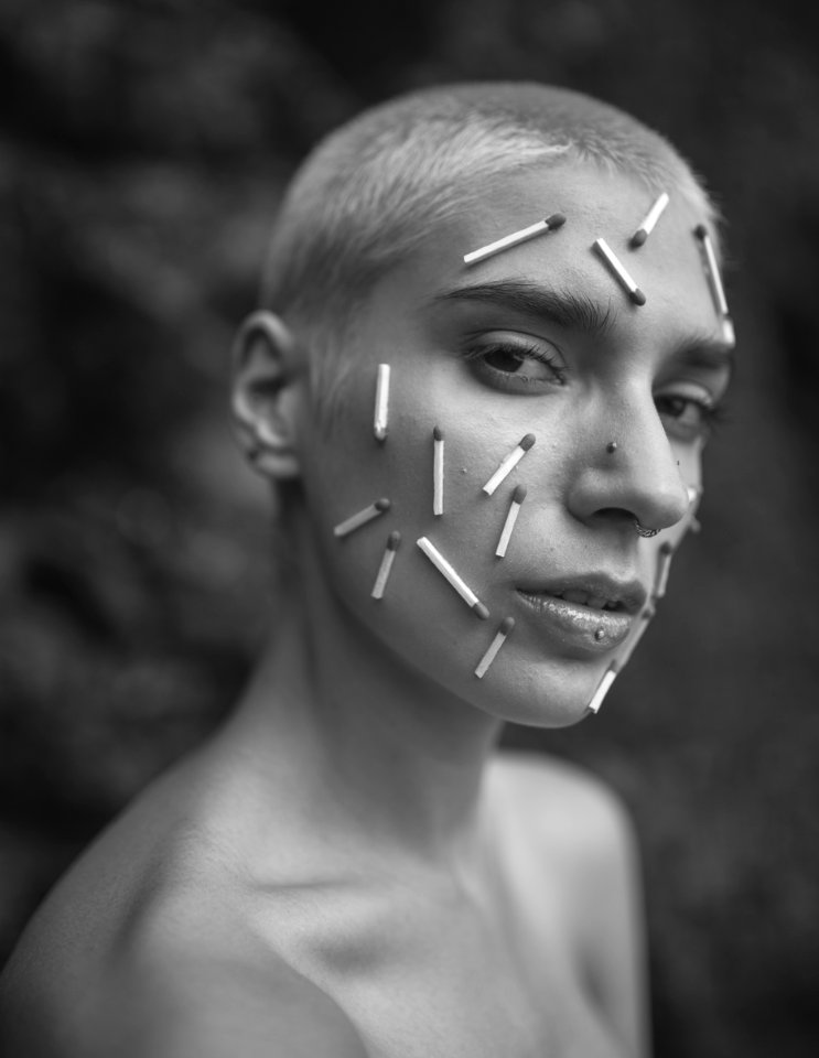 Grayscale Photo Of A Person With Matchsticks On Face