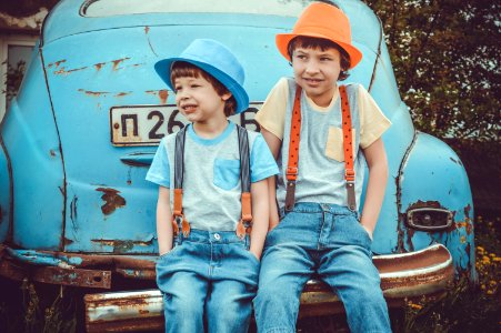 Two Boys Sitting On Classic Blue Cars Rear Bumper photo