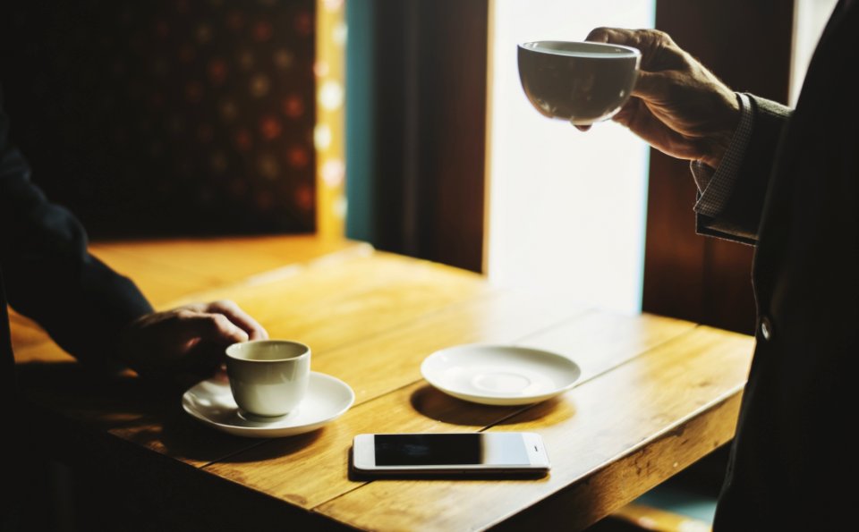 Man Holding Cup Near Table photo