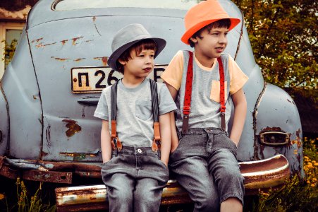 Two Boys Sitting On Vehicle Bumper