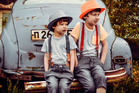 Two Boys Sitting On Vehicle Bumper photo