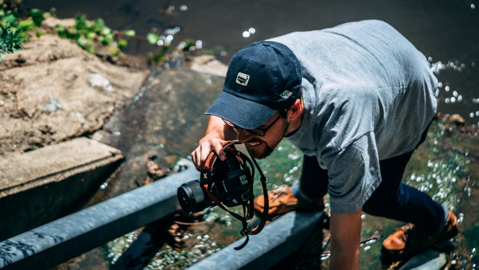 Man Holding Dslr Camera Wearing Cap photo