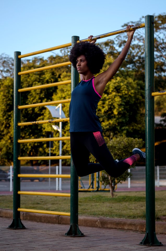 Woman Hanging On Climb Bar On Park